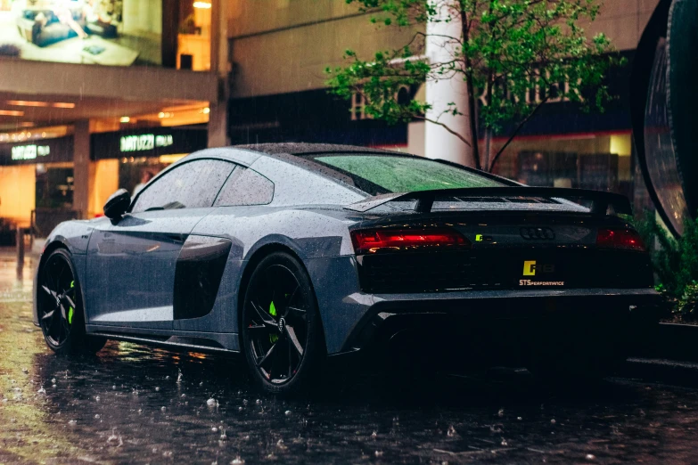 this grey sports car is parked in the rain