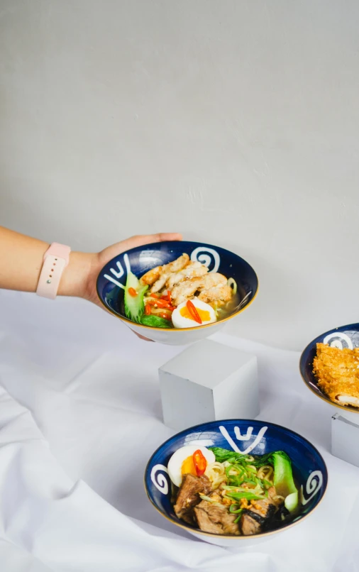 a person holds two plates of food, one of which has rice and vegetables