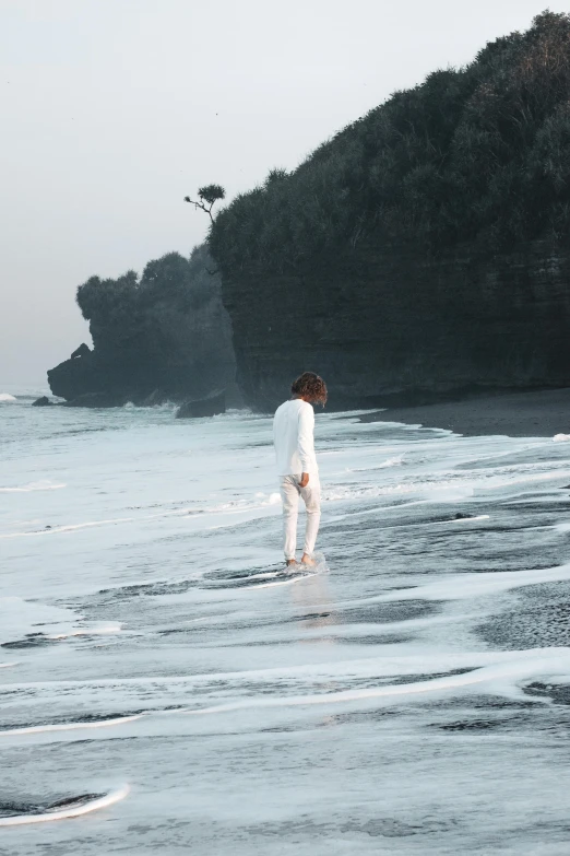 a woman in a white suit walking on the beach