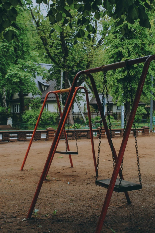 a wooden swing set with chains in a playground