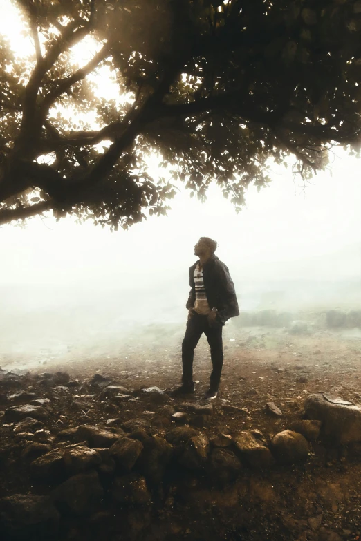 a man stands next to a tree and is taking a po