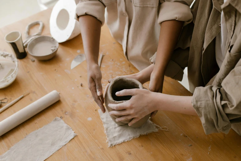 a person that is making a vase out of some clay