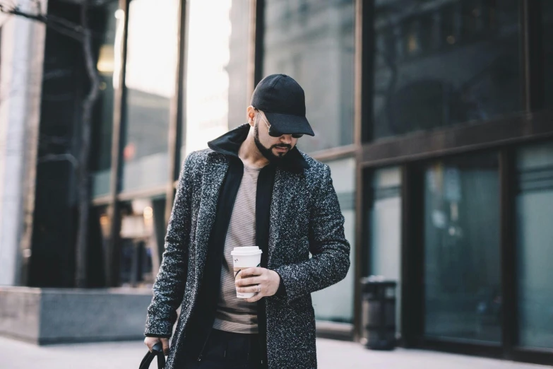 a man in winter clothing and a hat holding a coffee