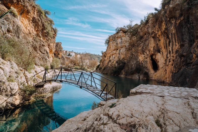 a bridge going over some water between two mountain cliffs