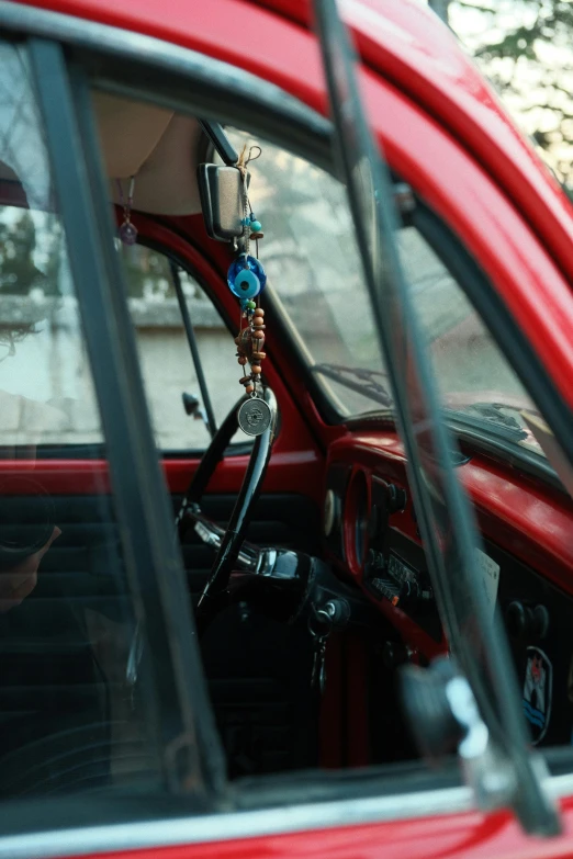 an old fashioned red car with a necklace hanging from the dash