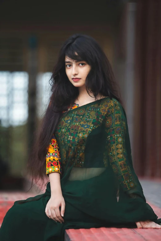 an indian woman with long dark hair sitting on a brick bench