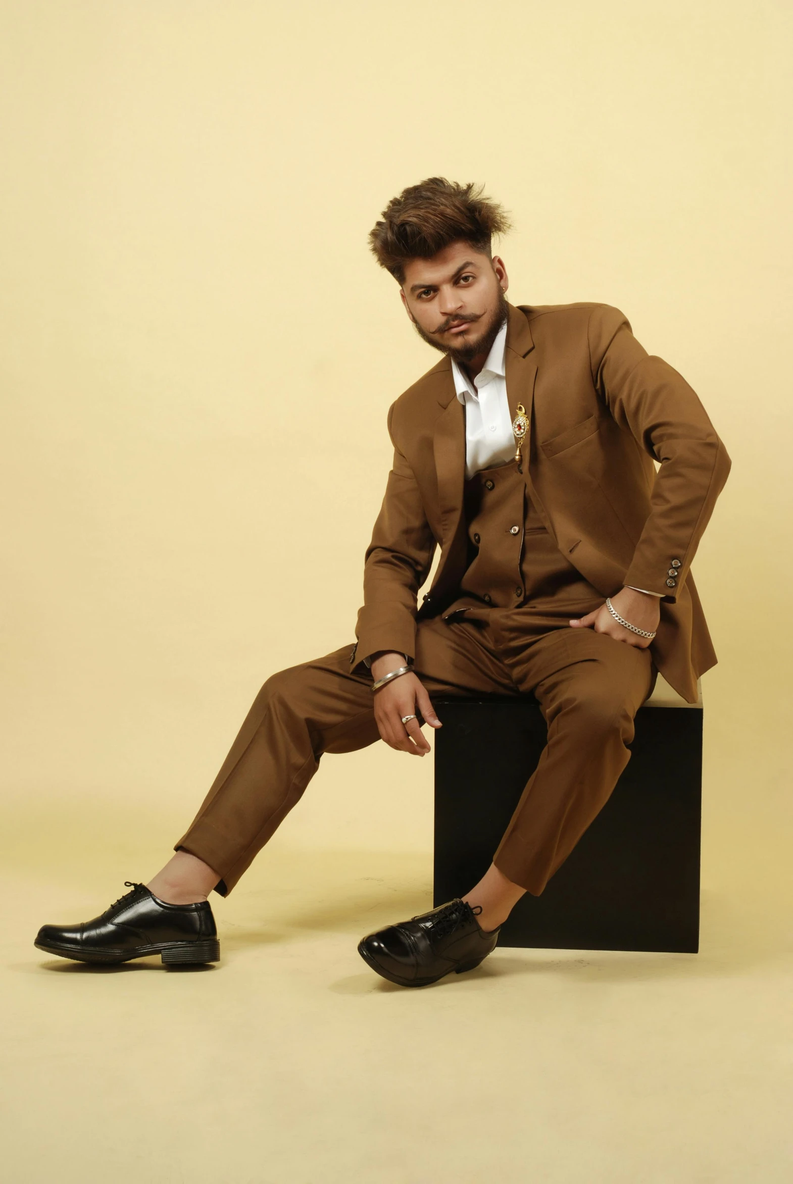 a man in a suit and tie sitting on a stool