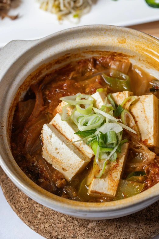 a bowl full of tofu and vegetables with chopsticks