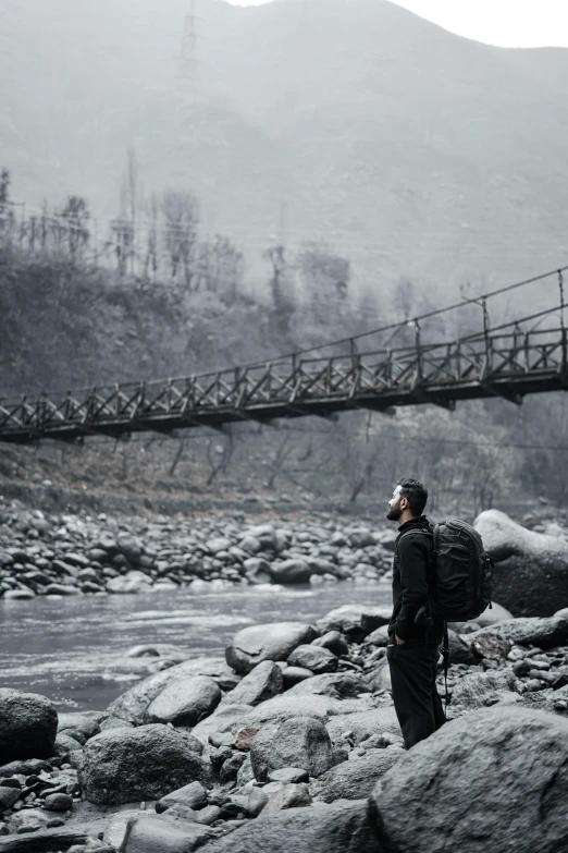 a man is standing on the rocks under an overpass