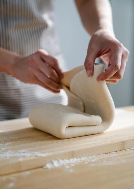 a person is making a pastry with a pair of hands