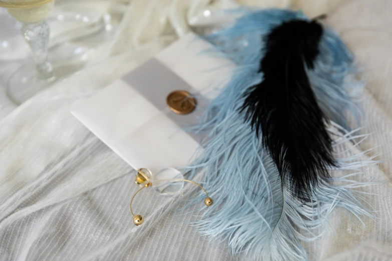 a feather next to a note, some wine glasses, and a bottle