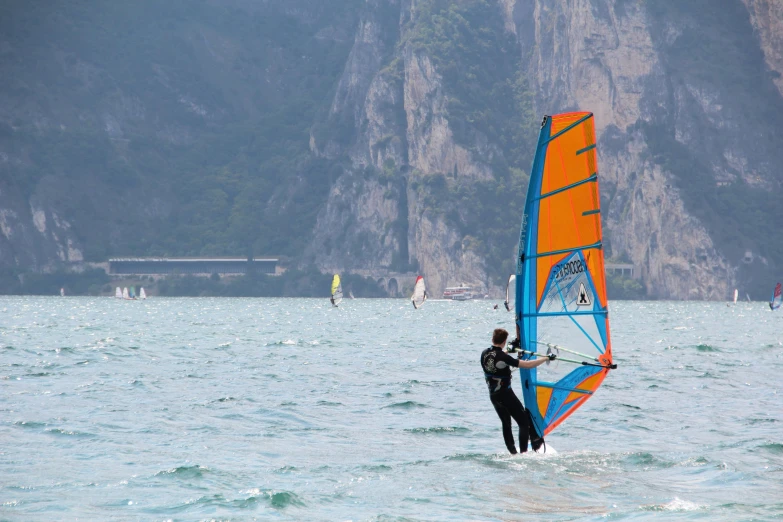 someone windsurfing with yellow and blue sails in water