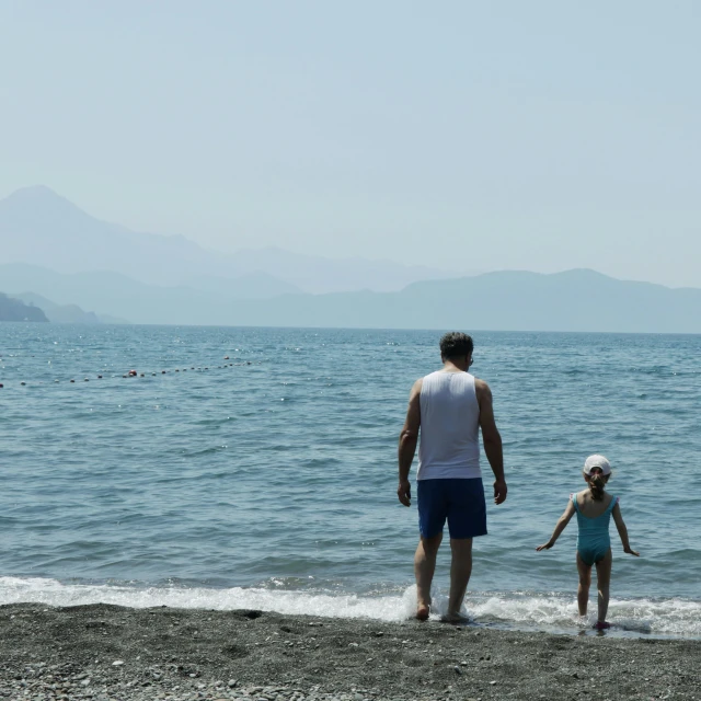 a man and two small children on the beach playing