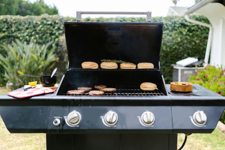 an outdoor grill that has hamburgers on the outside of it