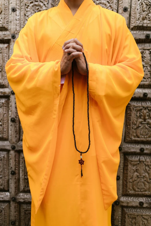 man in a bright orange robe with black cross necklace