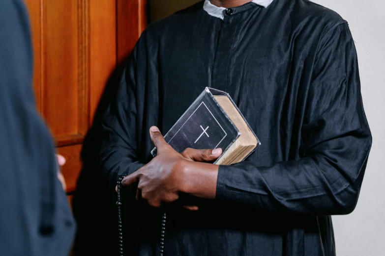 a person in a priest's robe and holding a religious item