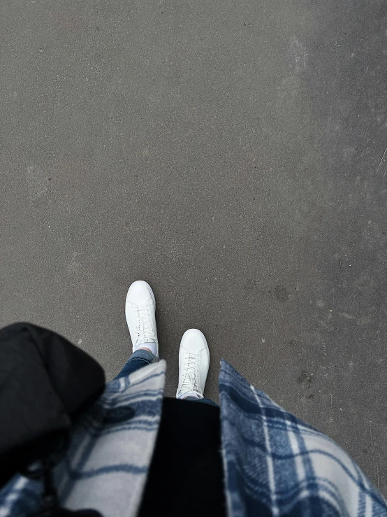 someone's white shoes standing on a black background