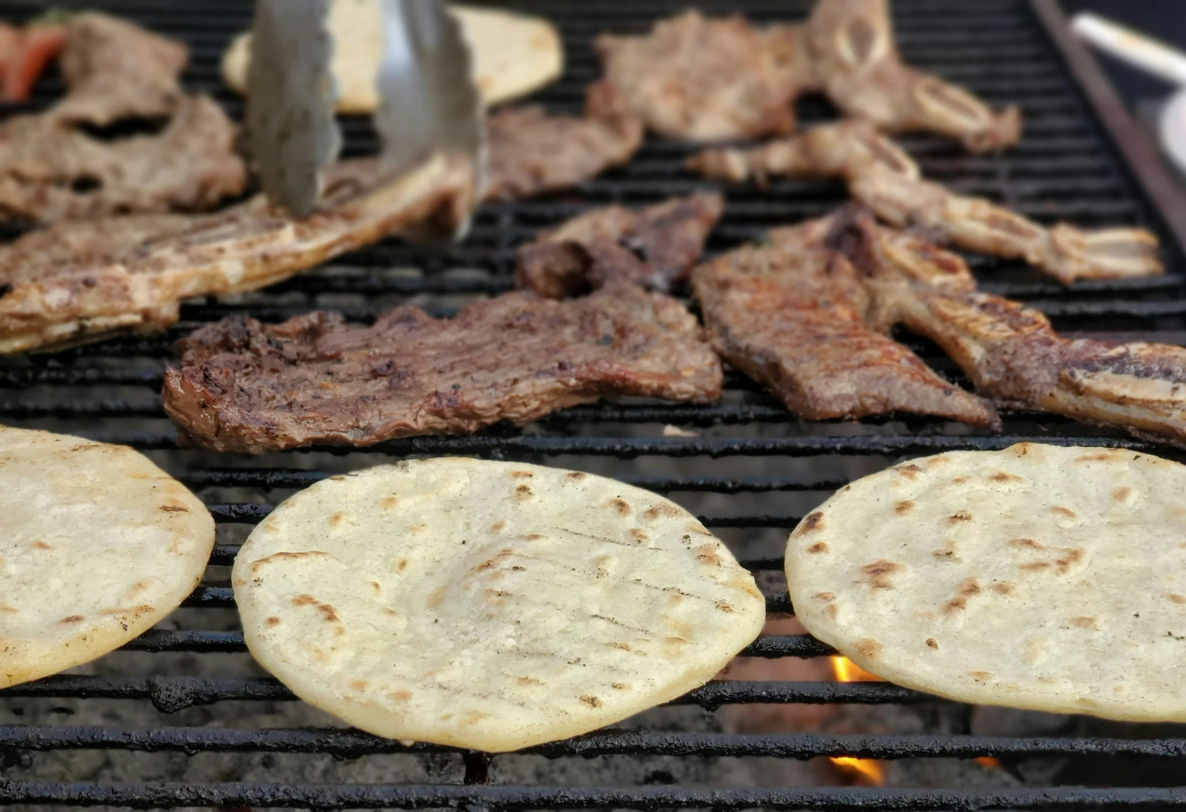 steaks are being prepared on an outdoor grill