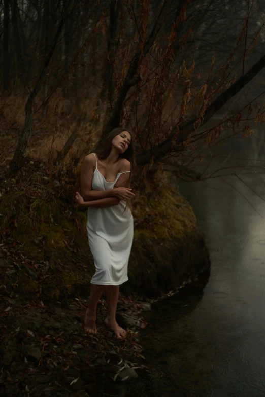 the woman is posing by the water and looking to her right