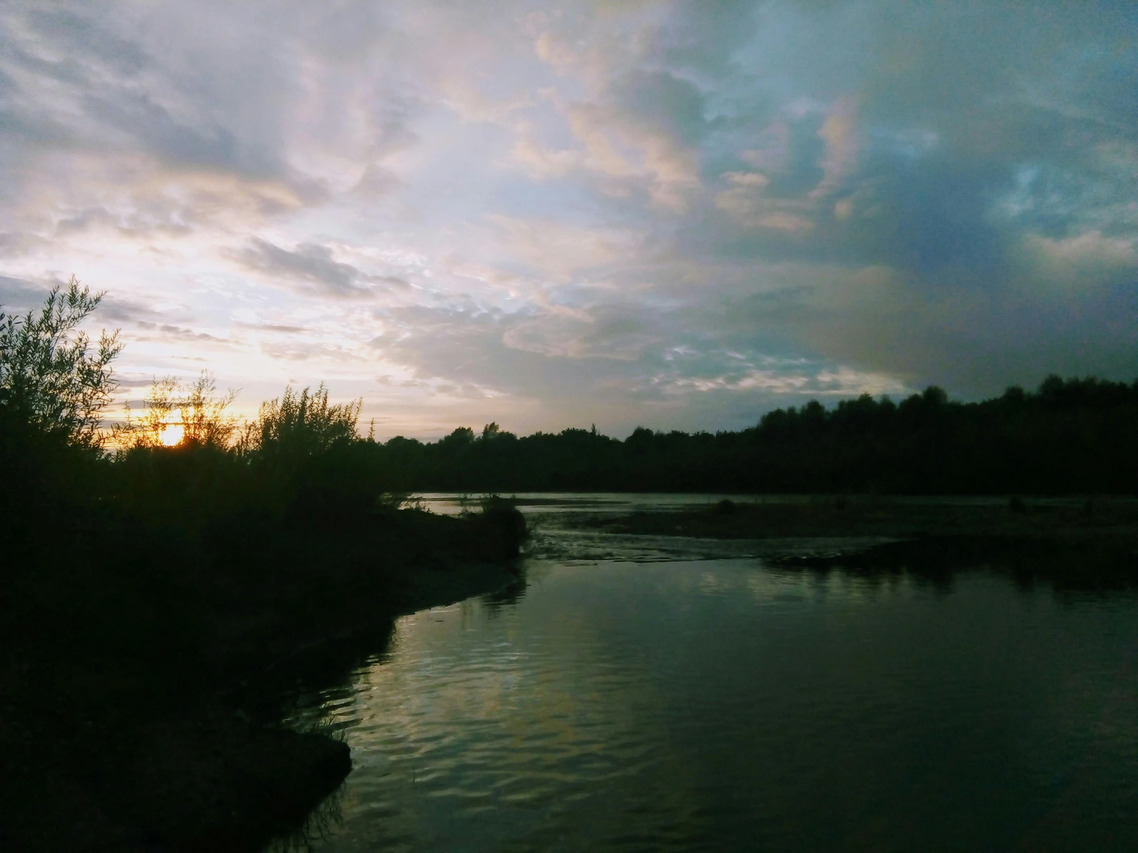 some clouds are in the sky over a river