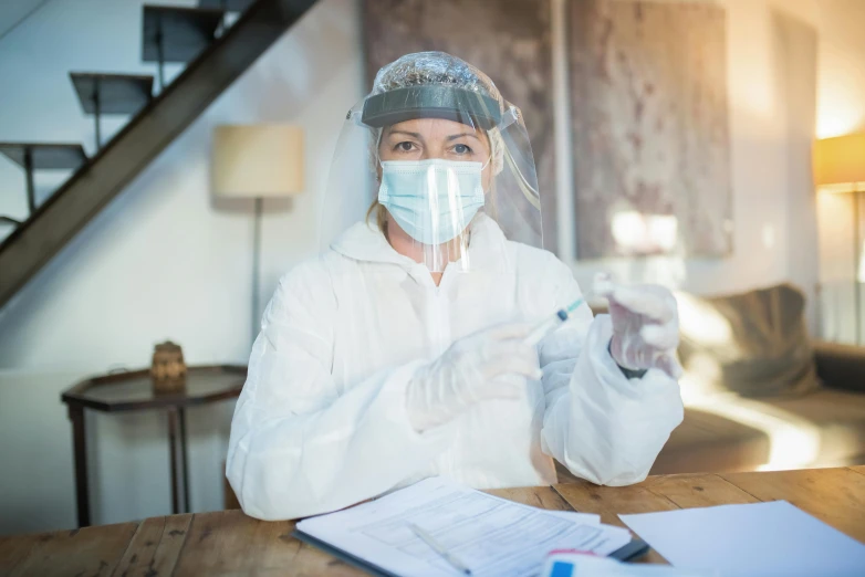 a woman wearing a mask sits at a desk