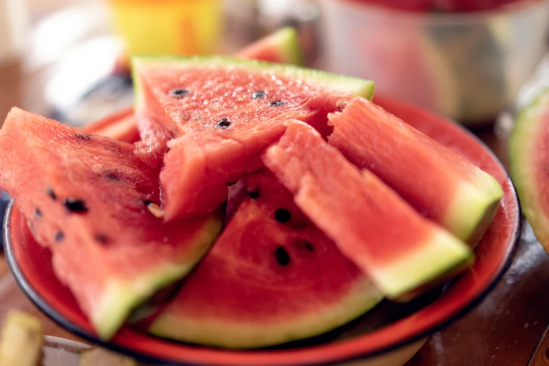 a red plate filled with sliced watermelon on top of a wooden table