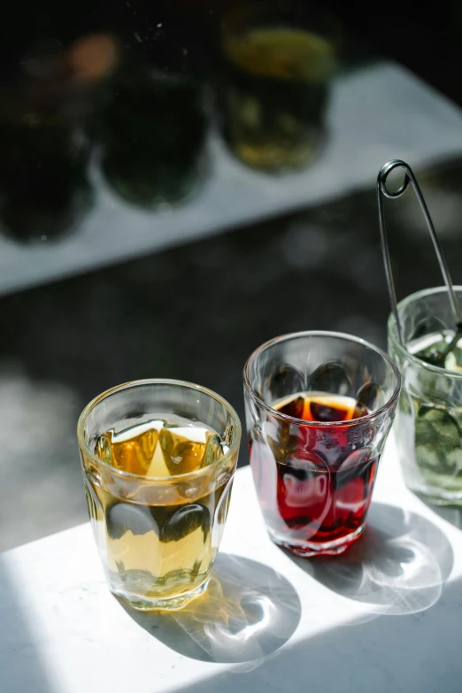 three glasses with drinks in them sit side by side