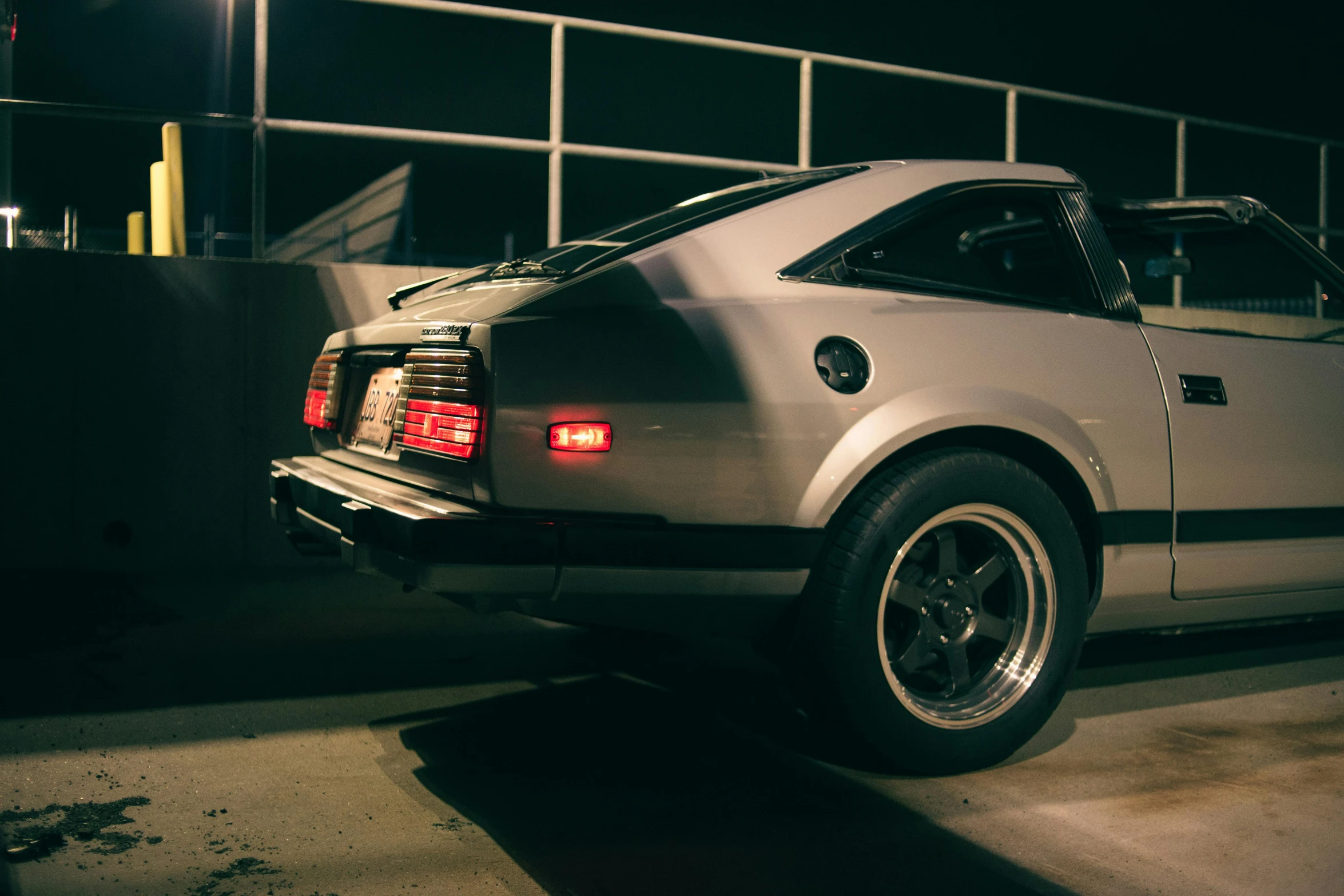 the back end of a white sports car parked in a parking lot