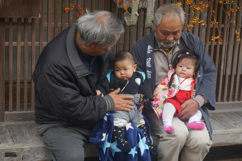 two men sit together with three babys