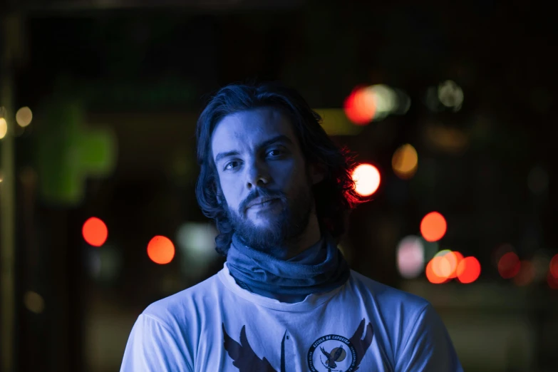 a man with long hair in a white shirt and blue scarf