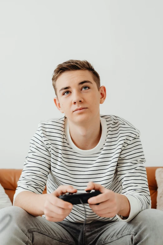 man holding remote controller up to his nose in front of white background