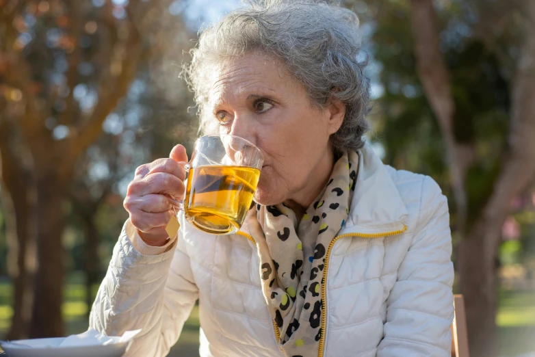 an older woman is sipping soing out of a glass