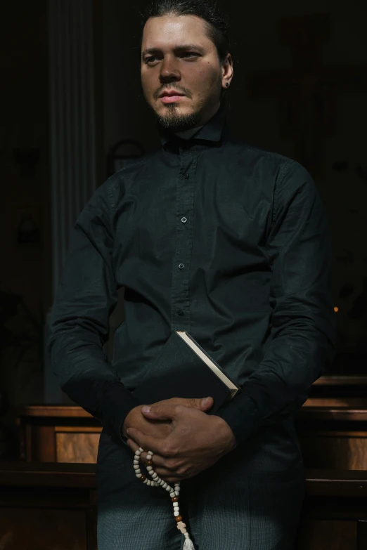 man standing near desk wearing black shirt and tie