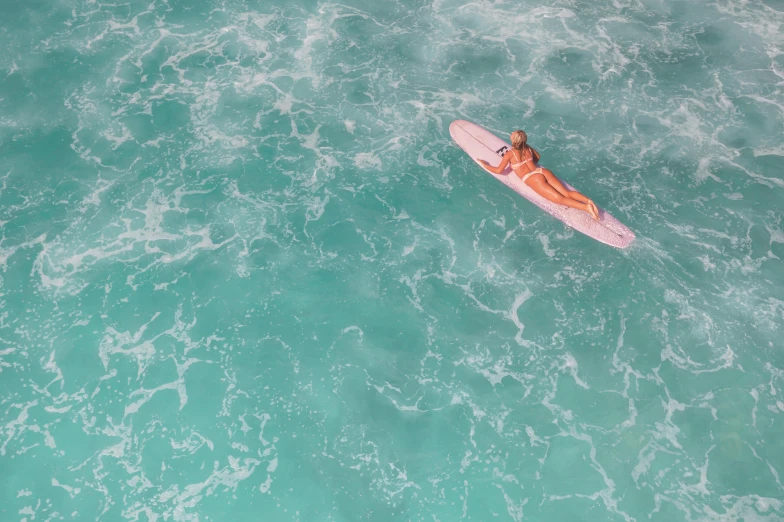 a young woman in a white swimsuit riding a surfboard in the ocean