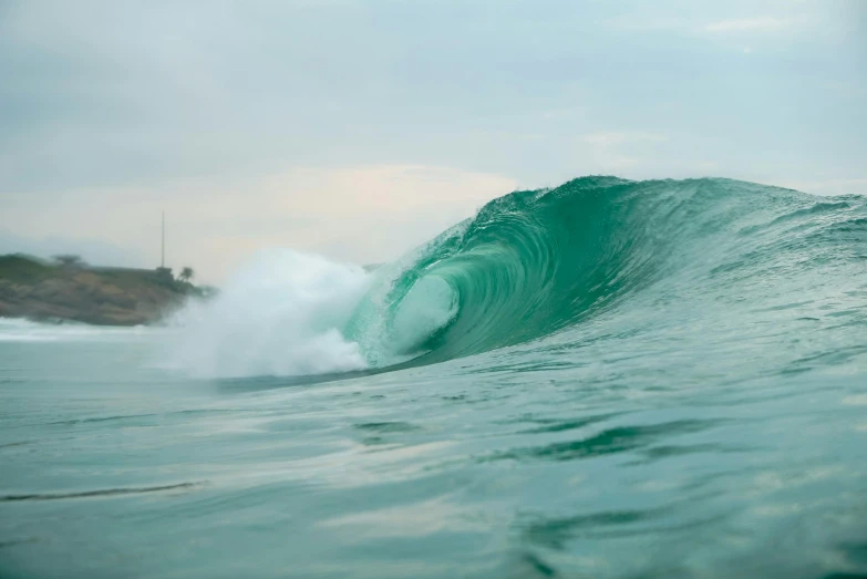 an ocean wave crashing on a cloudy day