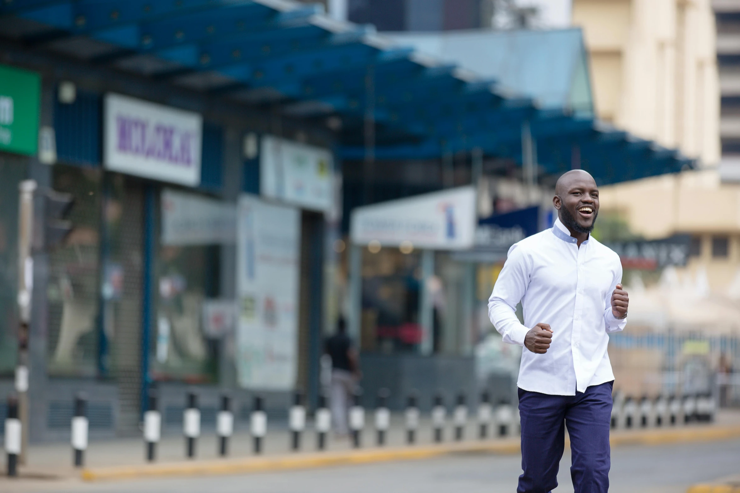 a black man running down the road in a white shirt