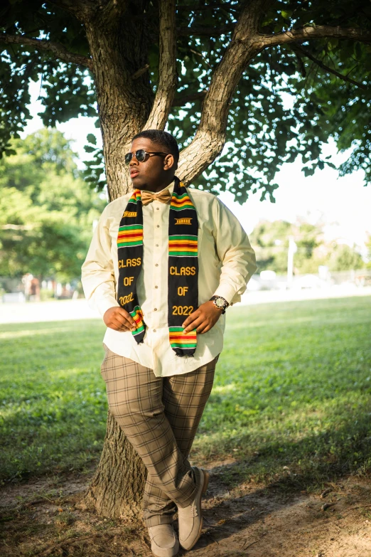 a man standing under a tree with his hands on his hips