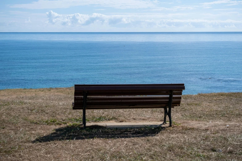 a bench sits alone in the grass near a body of water