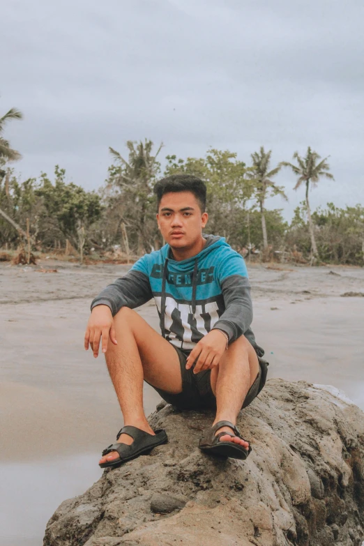 a man sitting on top of a rock at the beach