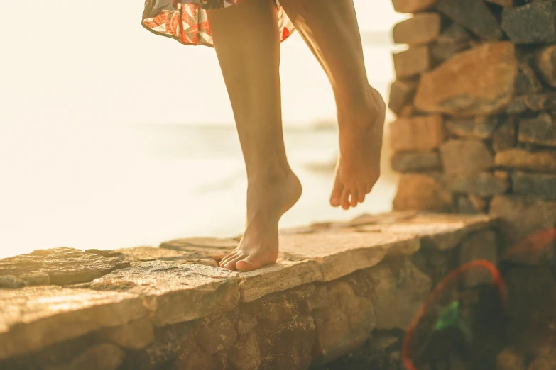 a barefoot woman's feet are on a ledge next to rocks