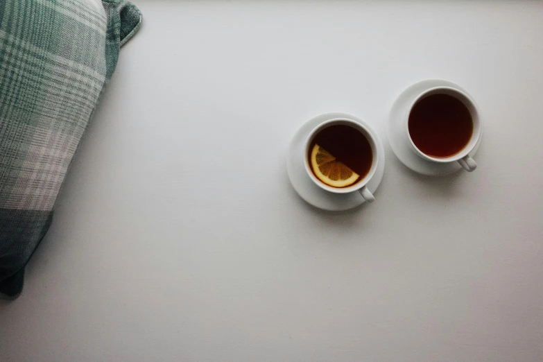 two cups filled with tea and orange peels sit next to each other