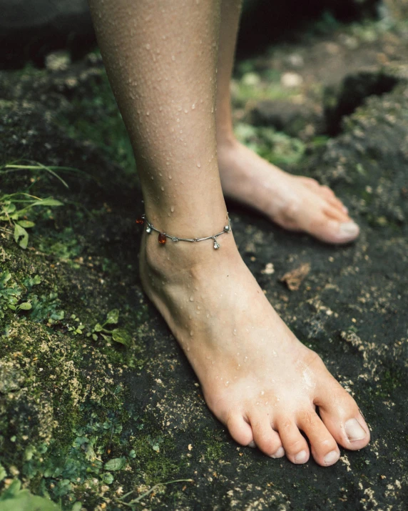 a bare foot wearing a gold and silver celet