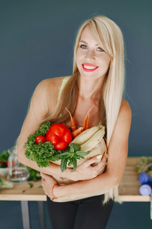 the woman smiles and holds a plate with vegetables