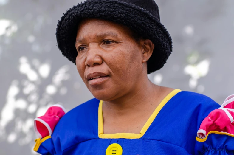 an older woman wearing a blue dress and black hat