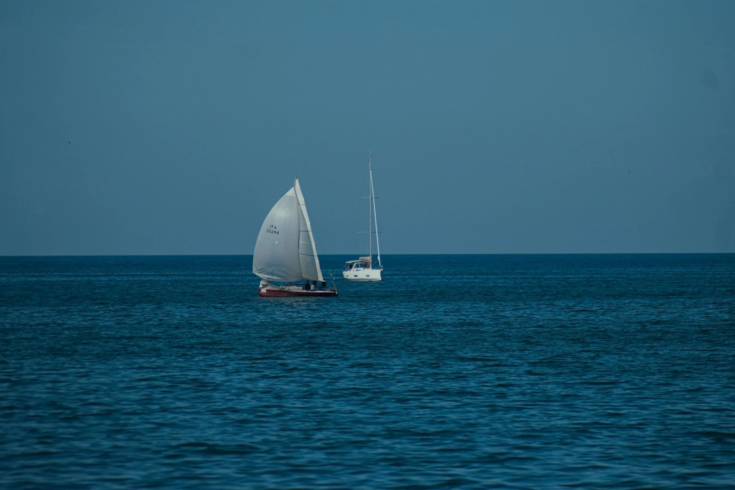 two small sail boats on calm blue waters