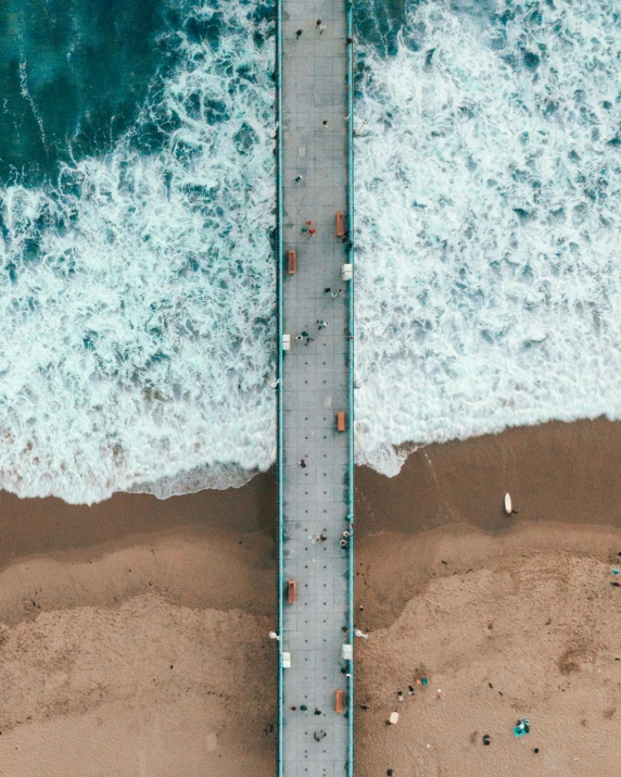 an aerial view of a street crossing over water to a beach