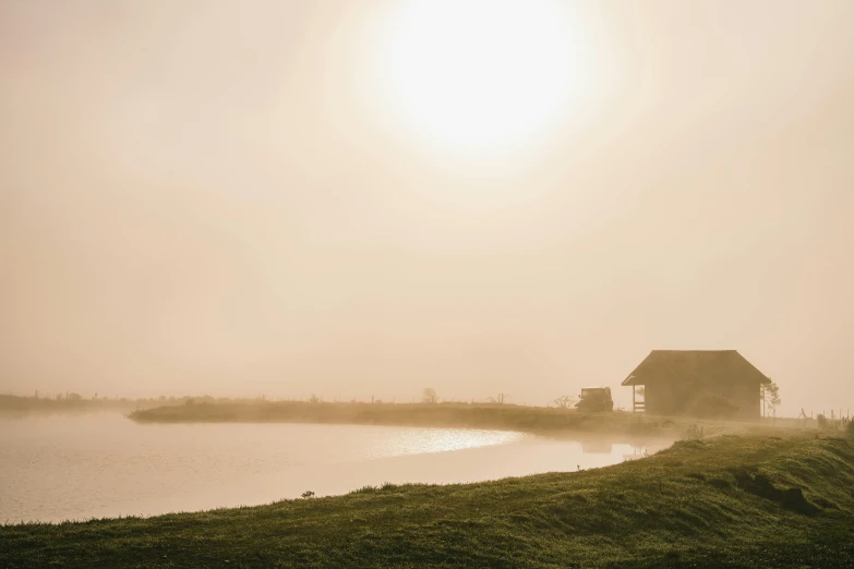 the sun over a house by a river