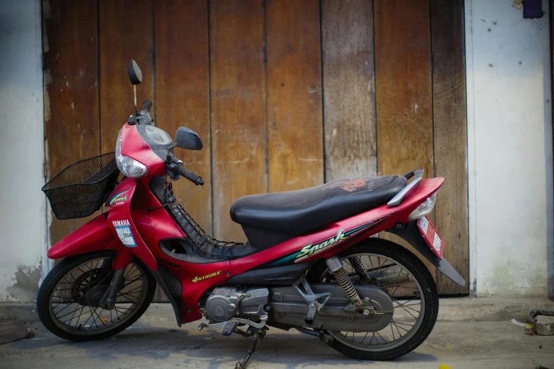 a red motor scooter parked in front of a brown wooden door