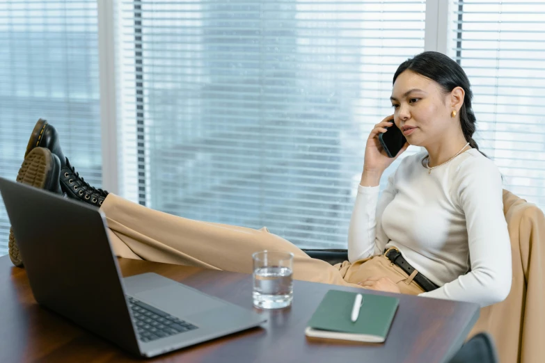 a woman sitting at a desk while talking on her cell phone