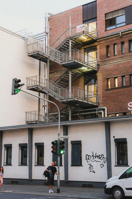 an old building with a fire escape, cars and a van